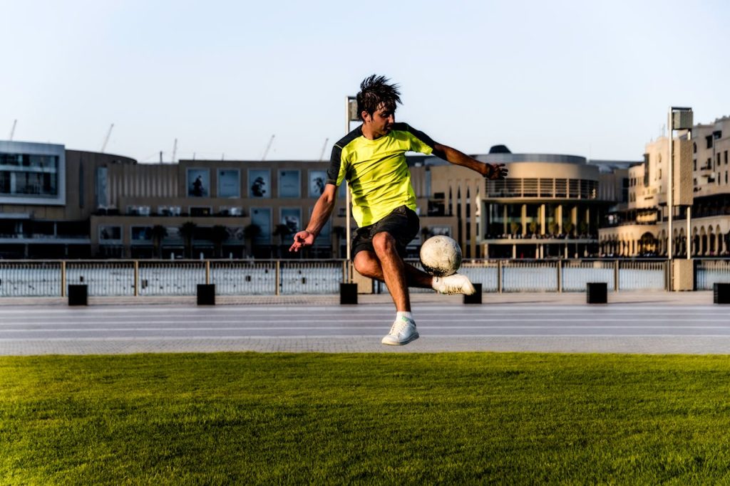 A young male soccer player skillfully kicks a ball on an open field during an outdoor practice session.